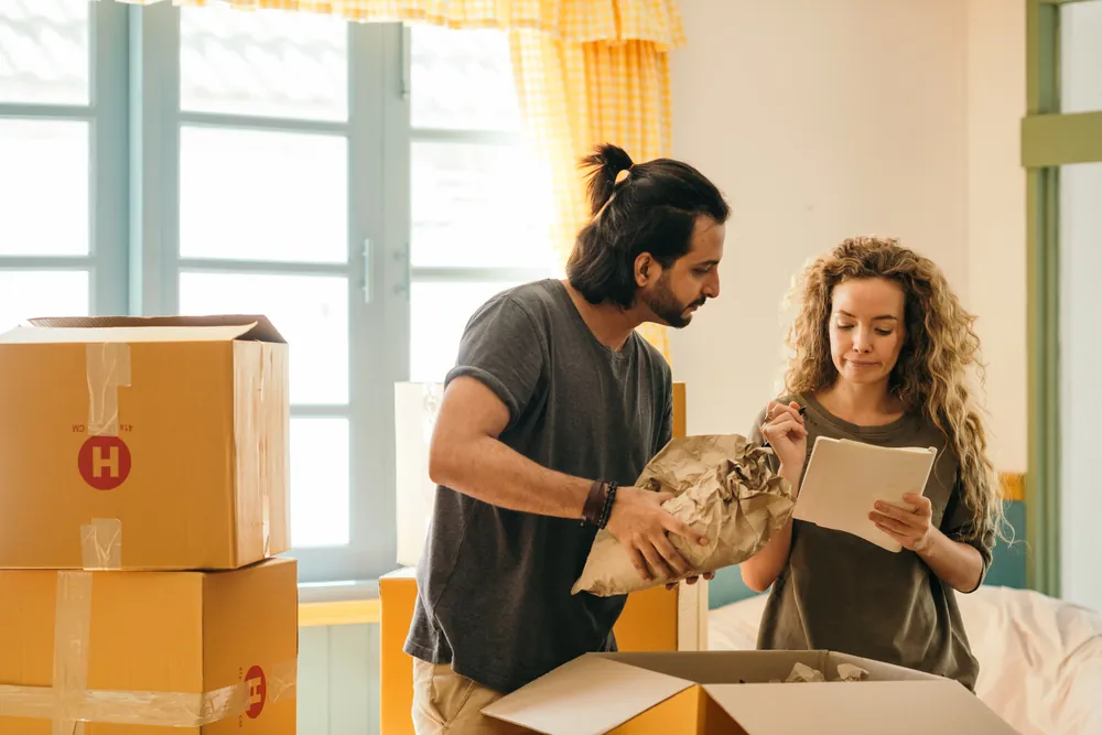 A couple unpacking boxes together in their new home, reflecting the settling-in period newcomers go through in Canada
