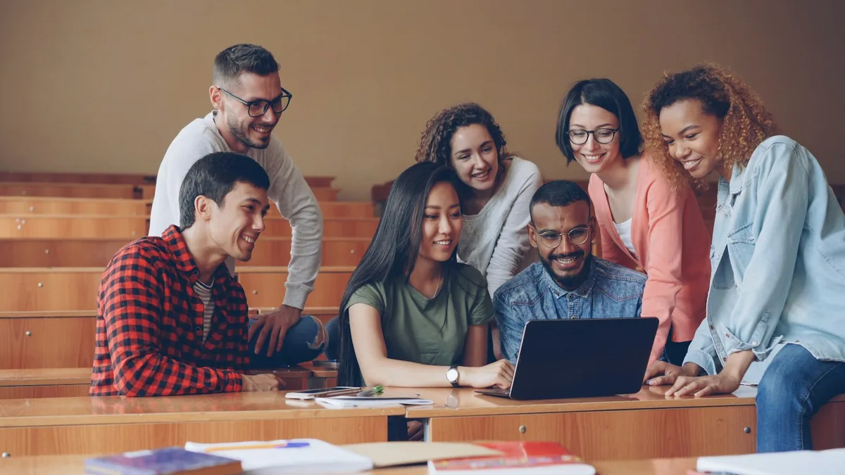 A diverse group of students collaborating around a laptop, representing learners choosing a college program in Canada in the age of AI