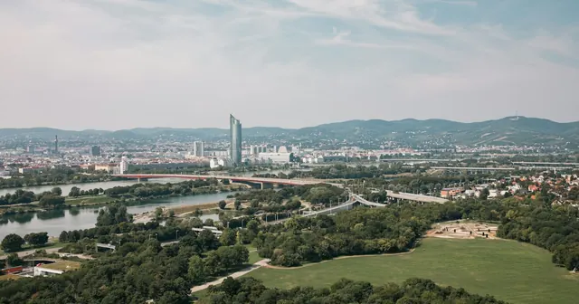 Aerial view of Vienna from the Donauturm, with the Danube, the Millennium Tower and green hills beyond the city