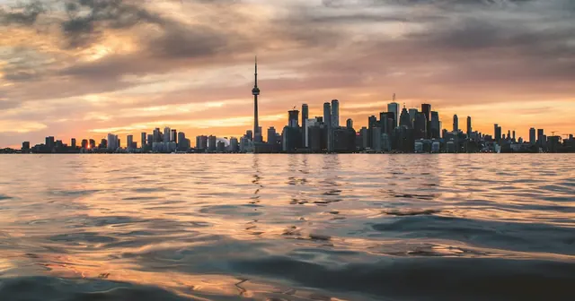The Toronto skyline and CN Tower silhouetted at sunset across the rippling water of Lake Ontario